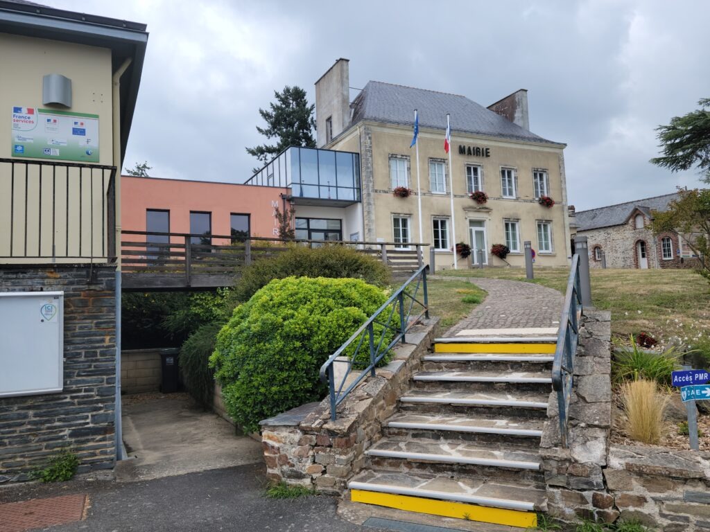 Escalier en pierre menant à une mairie, entouré de buissons, de pelouses et d'autres bâtiments.