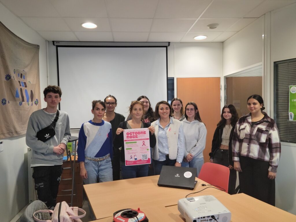 Un groupe de jeunes, une conseillère, la directrice et une intervenante, groupés derrière une affiche "Octobre Rose".