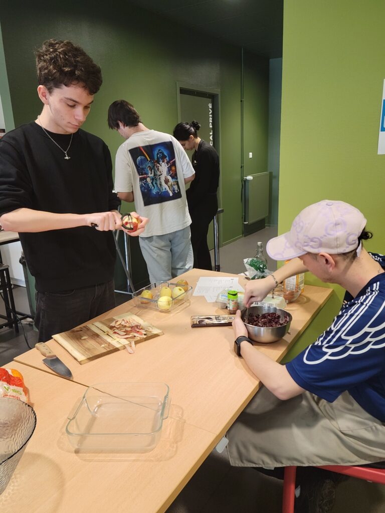 Deux jeunes en train de travailler des légumes autour d'une table.