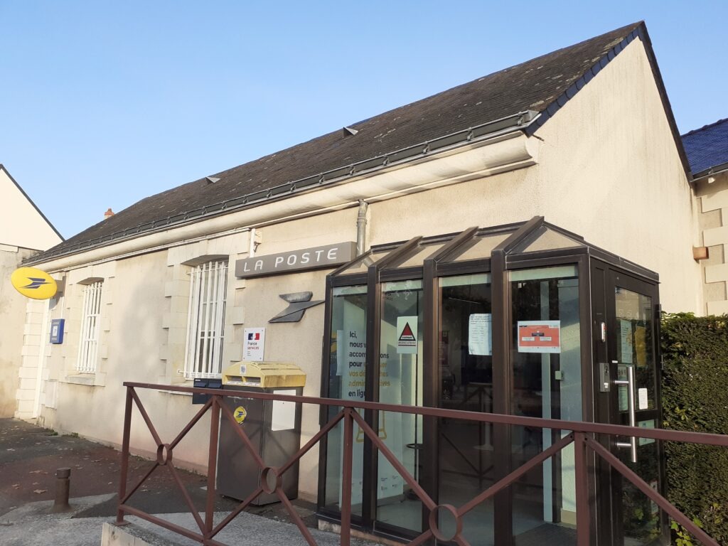 Bâtiment beige avec un sas d'entrée vitré marron et un logo "La Poste".