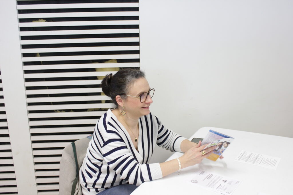 Une marraine derrière une table avec un prospectus.